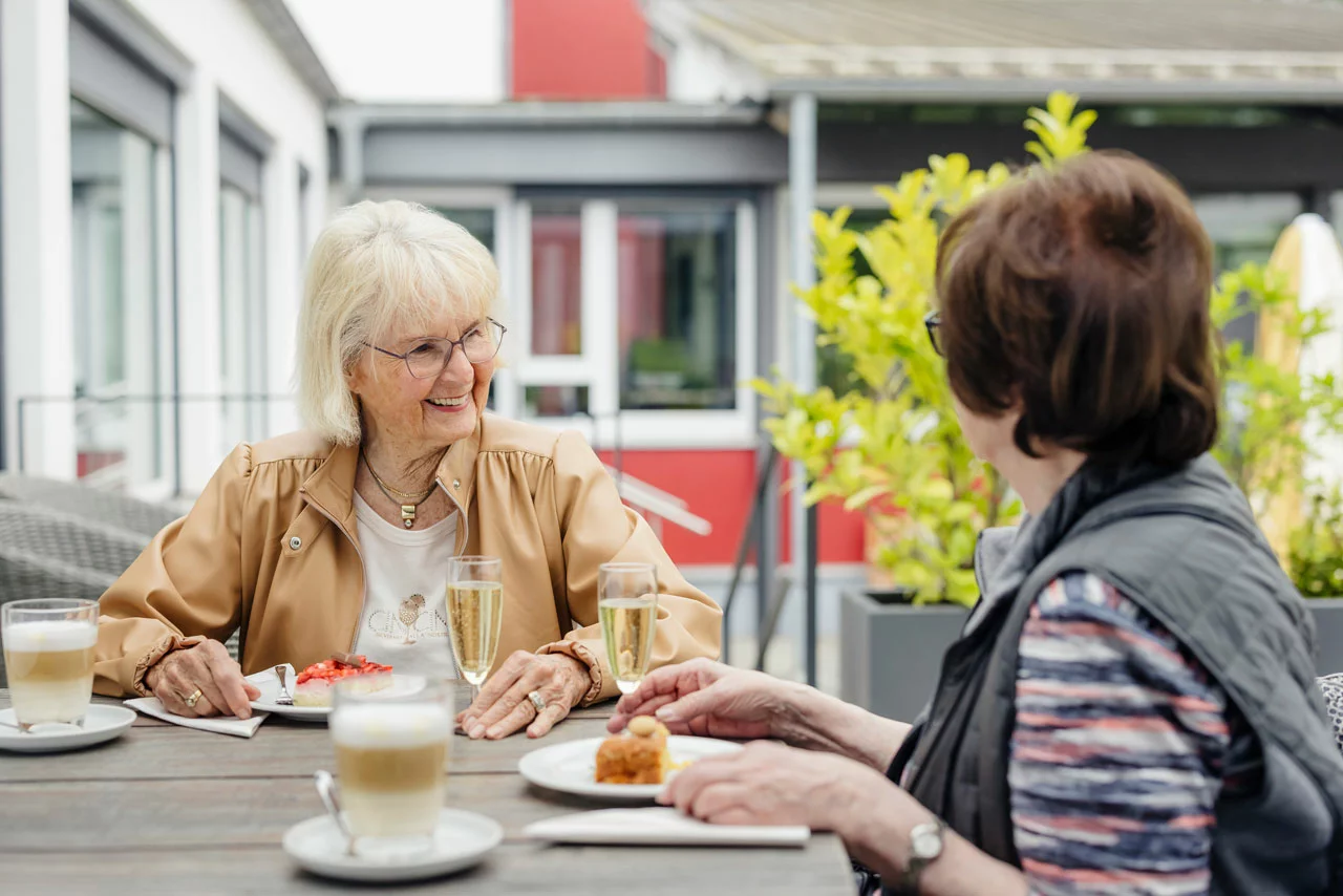 Zwei Seniorinnen trinken Kaffee auf der Terrasse des Café Sophie Gemeinsam statt einsam